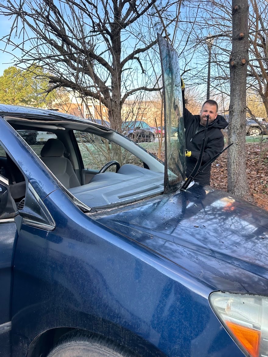 Technician removing a windshield from a blue vehicle