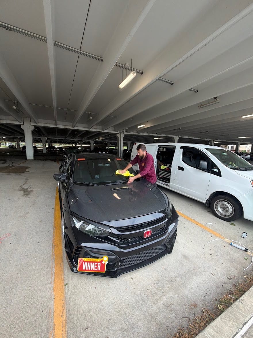 Finished windshield being wiped down on a black Honda Civic