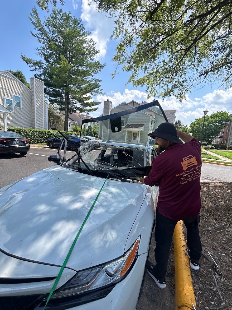 Technician removing a cracked windshield from a sedan