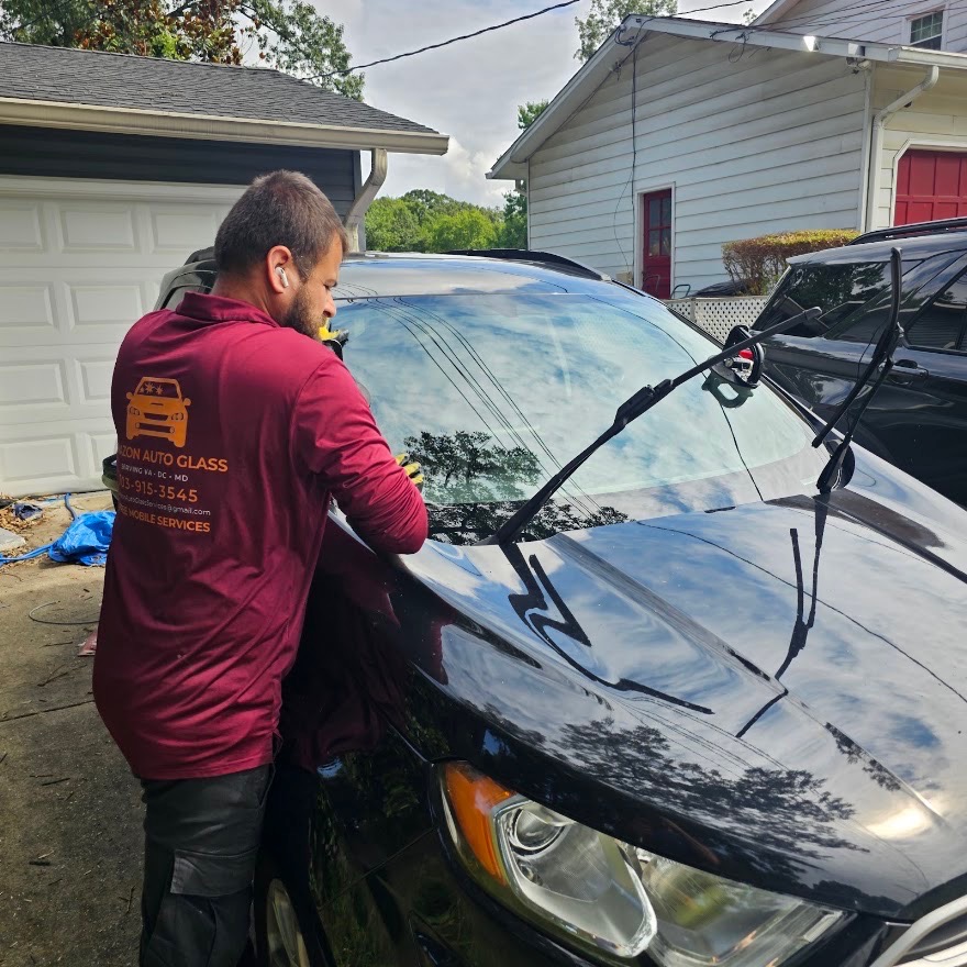 Technician setting a new windshield on a black SUV